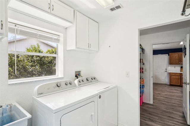 washroom with cabinet space, visible vents, dark wood finished floors, washer and dryer, and a sink