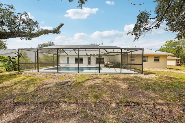 rear view of property featuring glass enclosure, a patio area, and an outdoor pool