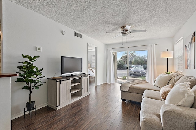 living area featuring baseboards, dark wood-type flooring, visible vents, and a ceiling fan