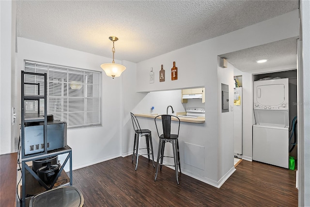 kitchen featuring a textured ceiling, under cabinet range hood, stacked washer and dryer, dark wood-style flooring, and electric range oven