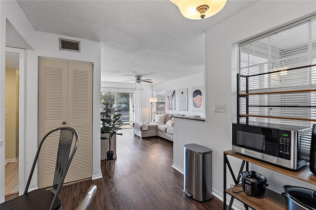 interior space featuring dark wood-style floors, baseboards, visible vents, and a textured ceiling