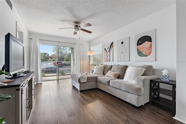 living area with dark wood-style flooring, visible vents, ceiling fan, and a textured ceiling