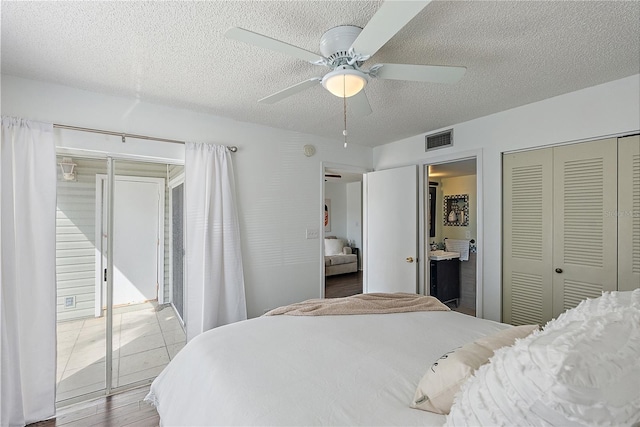 bedroom featuring visible vents, a ceiling fan, connected bathroom, wood finished floors, and a textured ceiling