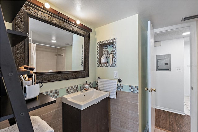 full bathroom with a shower with shower curtain, wood finished floors, visible vents, vanity, and tile walls