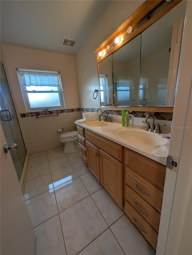 bathroom with tile patterned flooring, a sink, visible vents, and tile walls