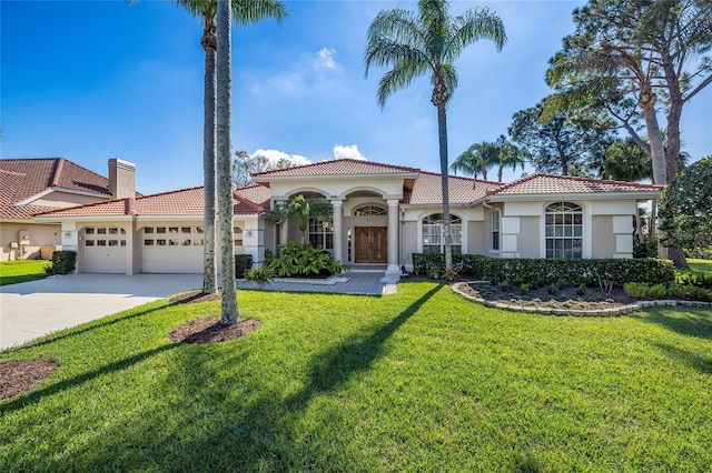 mediterranean / spanish home featuring a garage, a tiled roof, concrete driveway, stucco siding, and a front yard