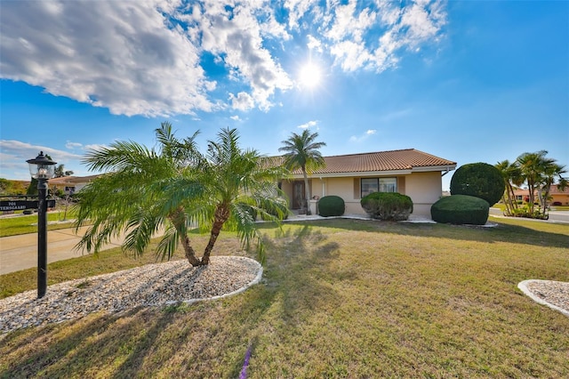 view of front of home featuring stucco siding, a front yard, and a tile roof