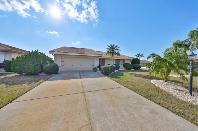 single story home with a tiled roof, a front yard, stucco siding, a garage, and driveway