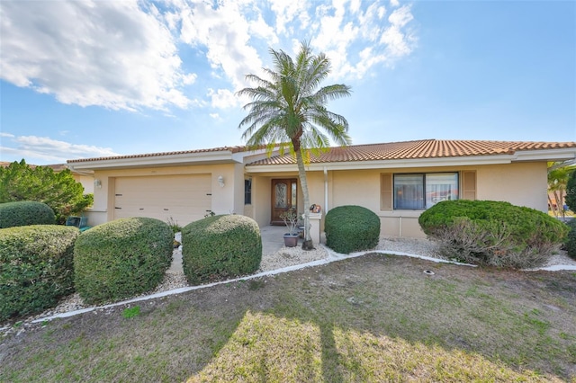 single story home with a tiled roof, an attached garage, and stucco siding