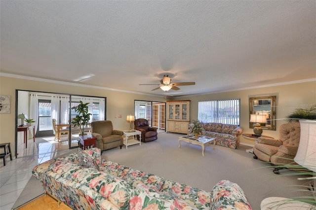 living area with a textured ceiling, ornamental molding, tile patterned flooring, and a ceiling fan