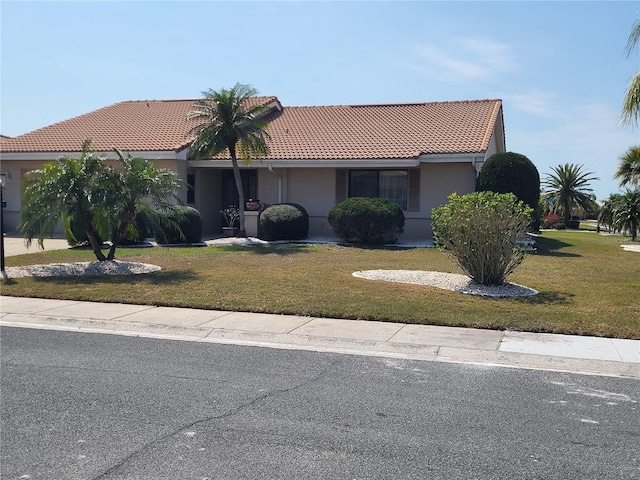 view of front of home with a front lawn, a tiled roof, and stucco siding