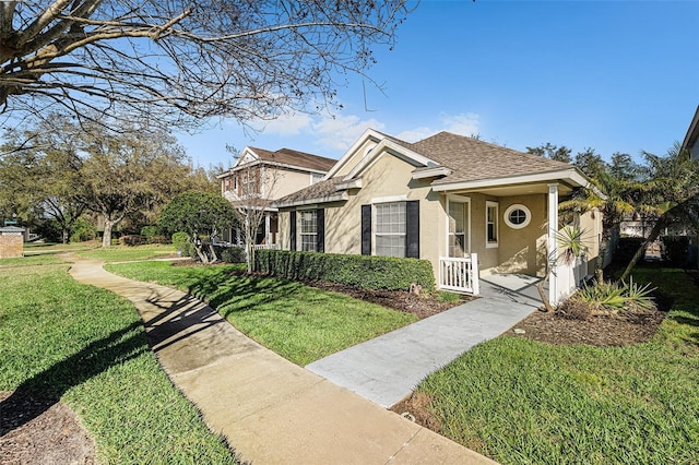 view of front of home featuring roof with shingles, a front lawn, and stucco siding