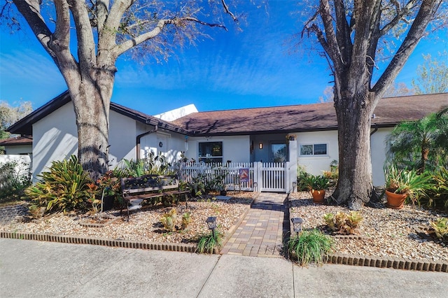 ranch-style house featuring fence and stucco siding