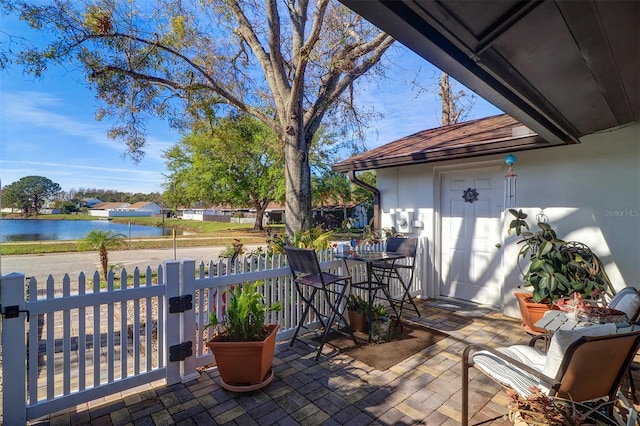 view of patio / terrace with outdoor dining area, a water view, and fence