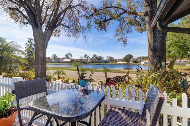 exterior space featuring outdoor dining area, a water view, and fence