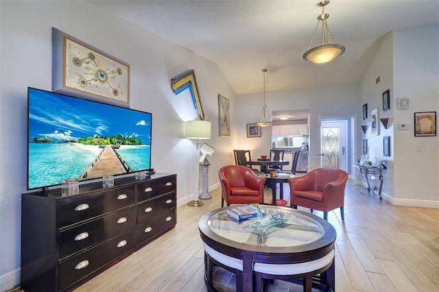 living area featuring lofted ceiling, baseboards, and light wood-style floors