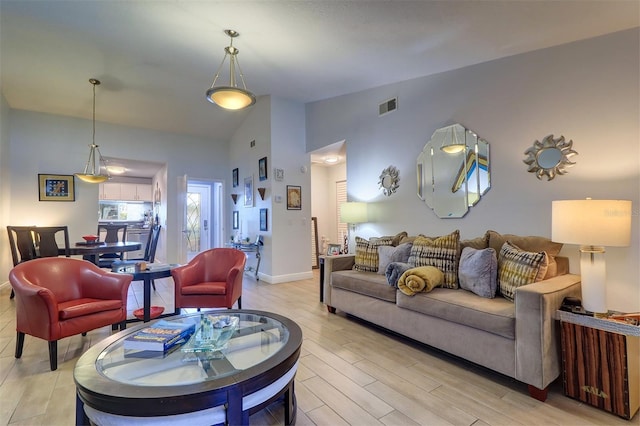 living room with high vaulted ceiling, visible vents, light wood-style flooring, and baseboards