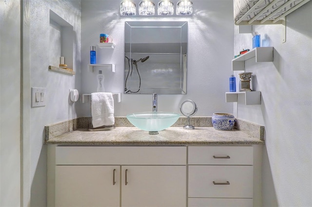 full bath with a shower, a textured wall, and vanity