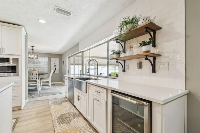 kitchen with stainless steel appliances, beverage cooler, light countertops, and a sink