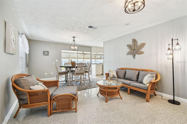 living area with a textured ceiling, speckled floor, visible vents, and baseboards