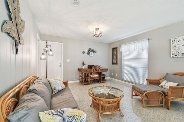 living area featuring visible vents, baseboards, and speckled floor