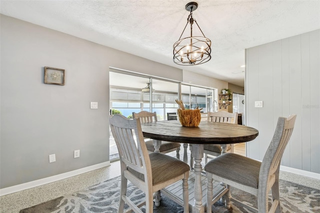 dining area featuring baseboards, a textured ceiling, an inviting chandelier, and speckled floor