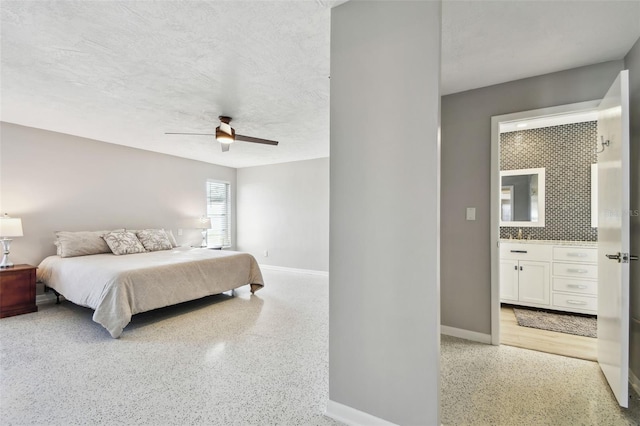 bedroom featuring baseboards, light speckled floor, a textured ceiling, and ensuite bathroom