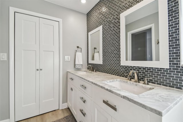 bathroom with tasteful backsplash, a sink, and wood finished floors