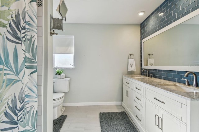 full bath with tasteful backsplash, a sink, toilet, and double vanity