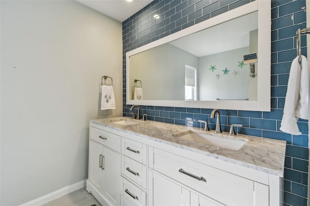 bathroom with baseboards, a sink, decorative backsplash, and double vanity