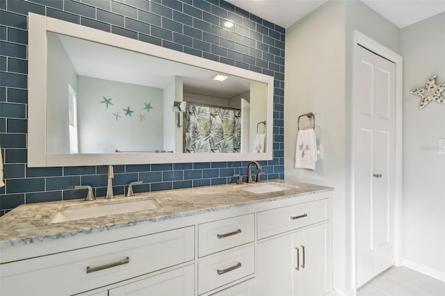 bathroom featuring double vanity, backsplash, a sink, and tile patterned floors