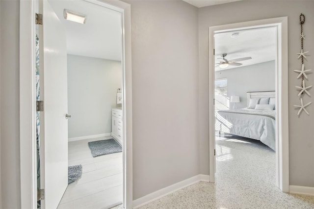 bathroom with ensuite bathroom, speckled floor, a ceiling fan, and baseboards