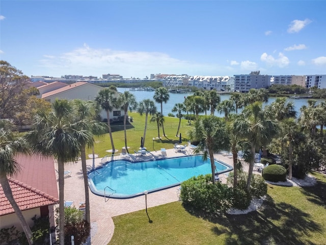 community pool with a water view, a patio area, and a yard