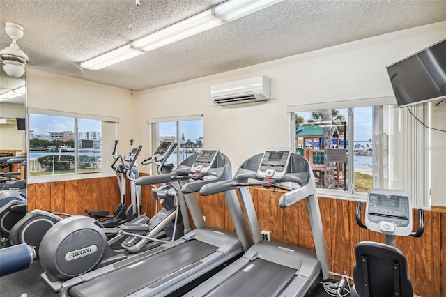 workout area featuring wood walls, a textured ceiling, and a wall mounted AC