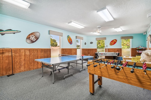 playroom with a textured ceiling, wainscoting, carpet flooring, and wooden walls