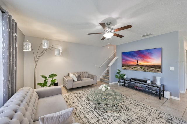 tiled living area featuring stairs, a ceiling fan, visible vents, and baseboards