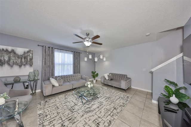 tiled living area featuring ceiling fan, a textured ceiling, and baseboards