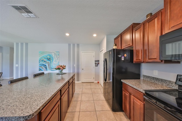 kitchen with black appliances, light tile patterned floors, visible vents, and a textured ceiling