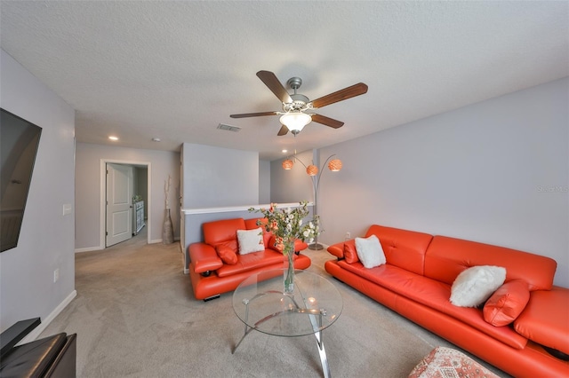 carpeted living area with a ceiling fan, visible vents, a textured ceiling, and baseboards