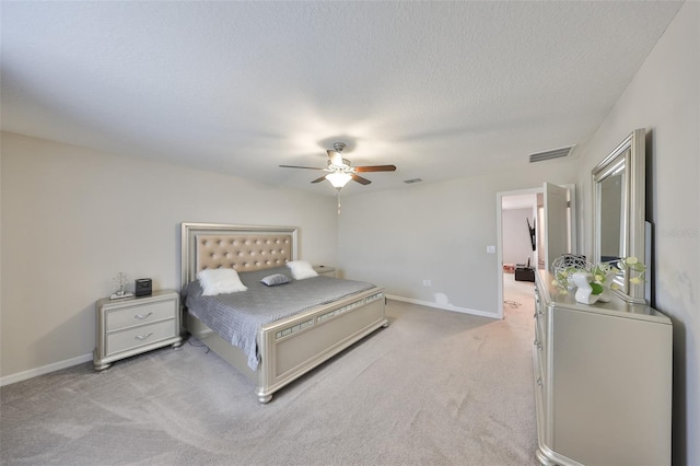 bedroom featuring baseboards, visible vents, light carpet, and a textured ceiling