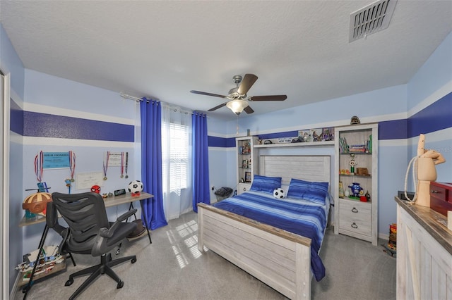 carpeted bedroom featuring a textured ceiling, ceiling fan, and visible vents