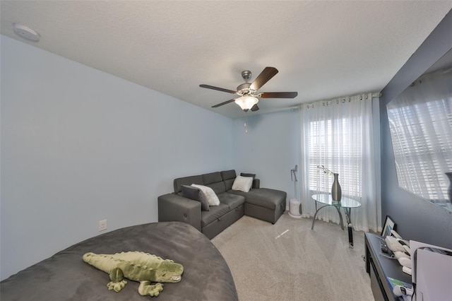 living area with a textured ceiling, ceiling fan, and light colored carpet