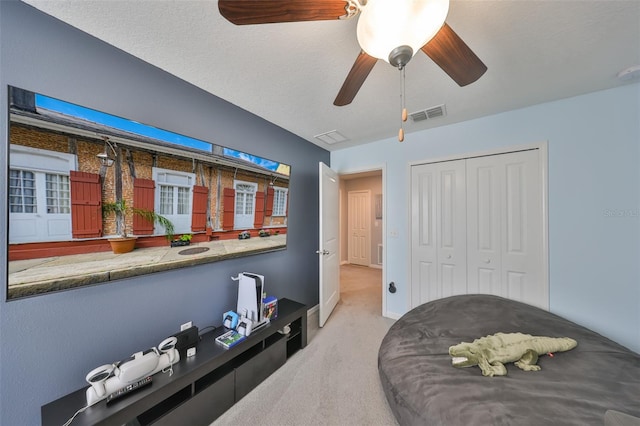 carpeted bedroom with a closet, visible vents, ceiling fan, a textured ceiling, and baseboards