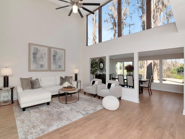 living area featuring a ceiling fan, baseboards, and wood finished floors