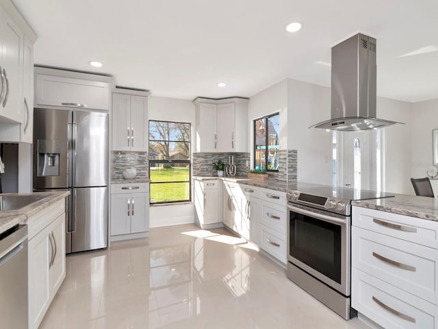 kitchen with light stone counters, recessed lighting, appliances with stainless steel finishes, tasteful backsplash, and island exhaust hood