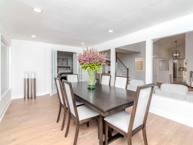 dining space with a textured ceiling, light wood finished floors, stairway, and recessed lighting