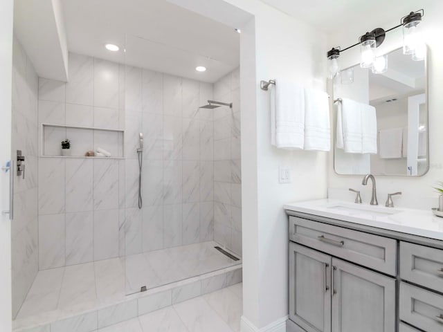 bathroom featuring tiled shower, vanity, and recessed lighting