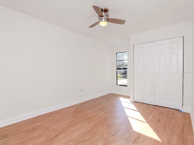 unfurnished bedroom with baseboards, a closet, a ceiling fan, and light wood-style floors