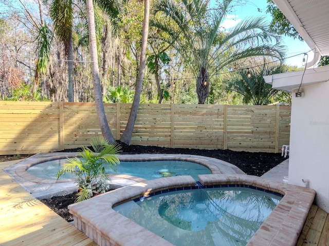 view of swimming pool featuring fence and a pool with connected hot tub