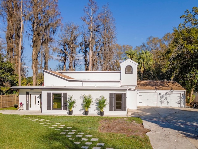 mid-century home featuring driveway, a front yard, fence, and stucco siding